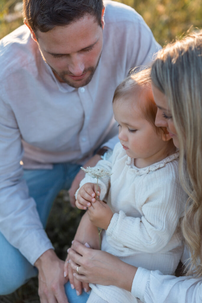 Ein Mädchen schaut mit seinen Eltern eine Blume an bei einem Familienshooting in Wittlich